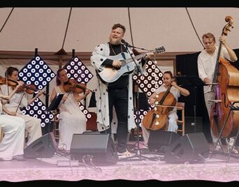 Foto af en gruppe musikere med guitarer og strygeinstrumenter.