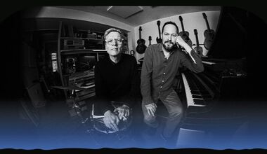 Det sort-hvide foto af to musikere, der står sammen foran flere musikinstrumenter.