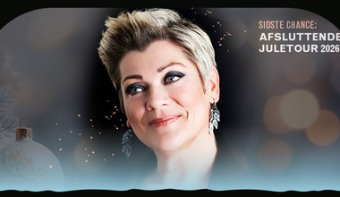 Billedet viser Ann Mette Elten, der smiler foran en julestemningsfuld baggrund.