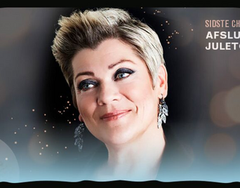 Billedet viser Ann Mette Elten, der smiler foran en julestemningsfuld baggrund.